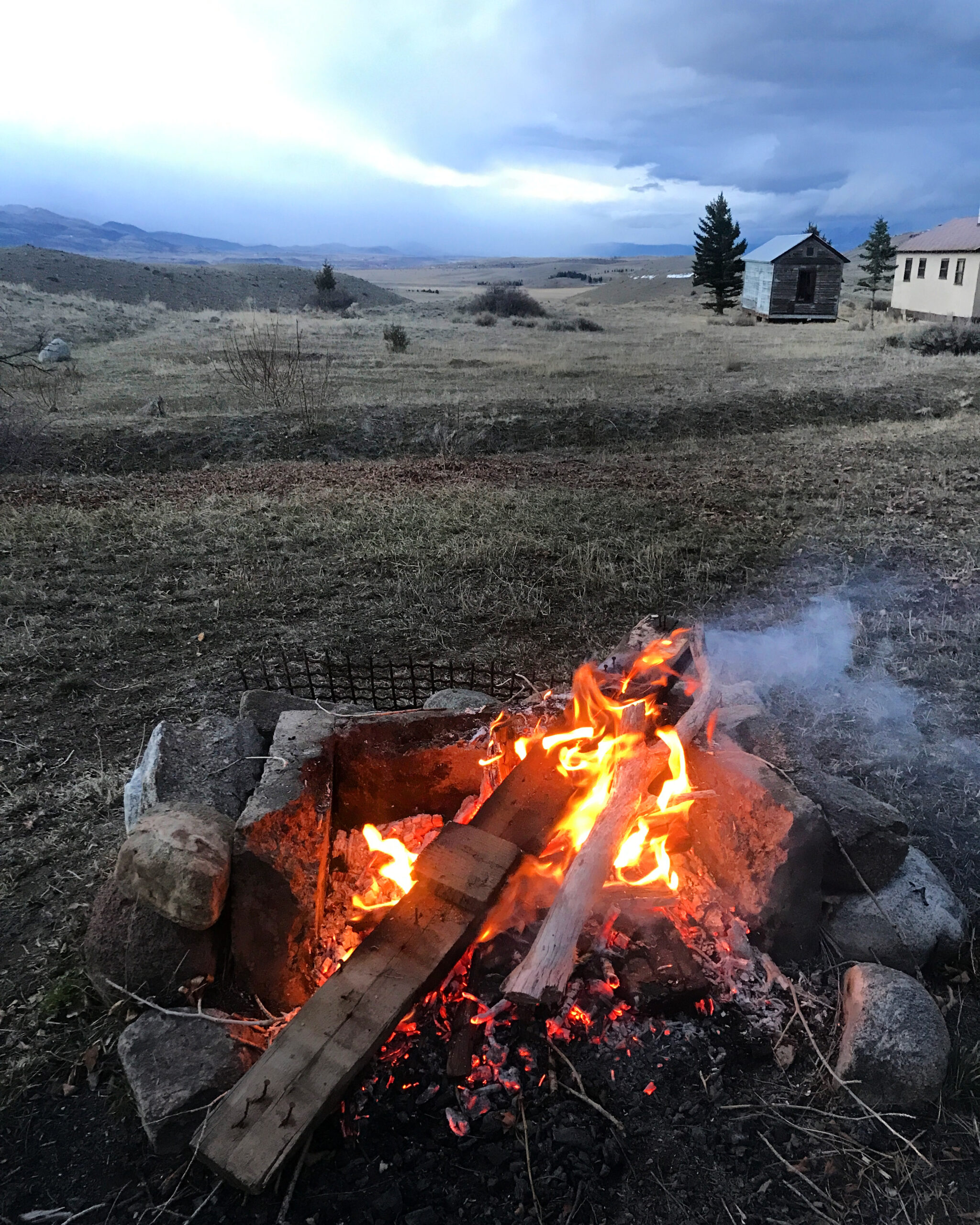 Scrapwood fire in firepit in foreground. Long view of Paradise Valley with low clouds.